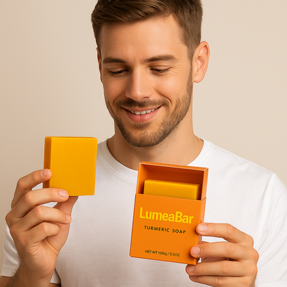 Junger Mann in weißem T-Shirt betrachtet eine LumeaBar-Kurkuma-Seife, die er gerade aus der geöffneten Verpackung nimmt.